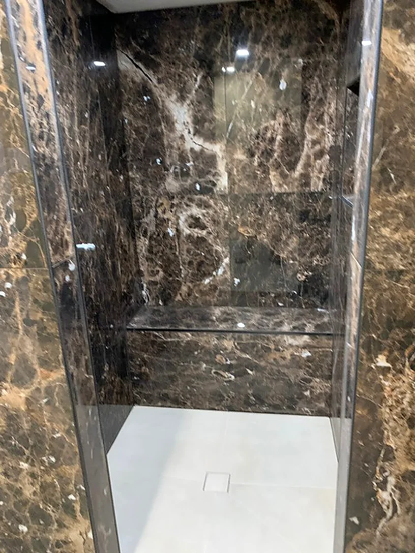 Dark marble-look shower with a bench
