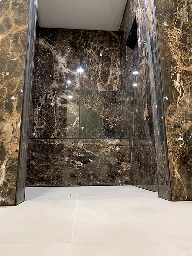 Dark marble-look shower with a bench
