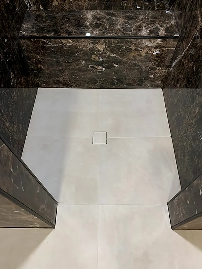 Dark marble-look shower with a bench