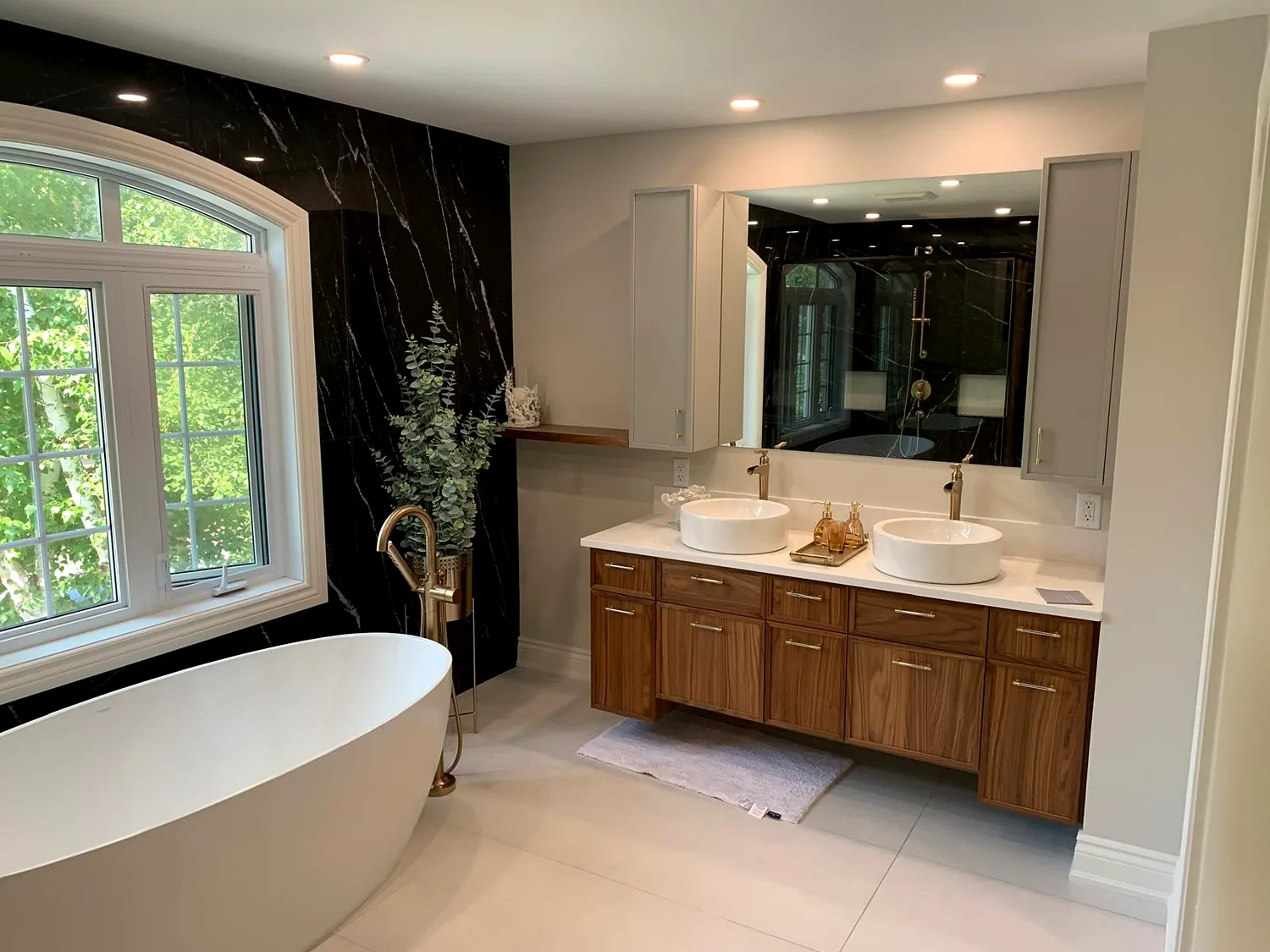 Black marble-look feature wall with a freestanding tub and double vanity